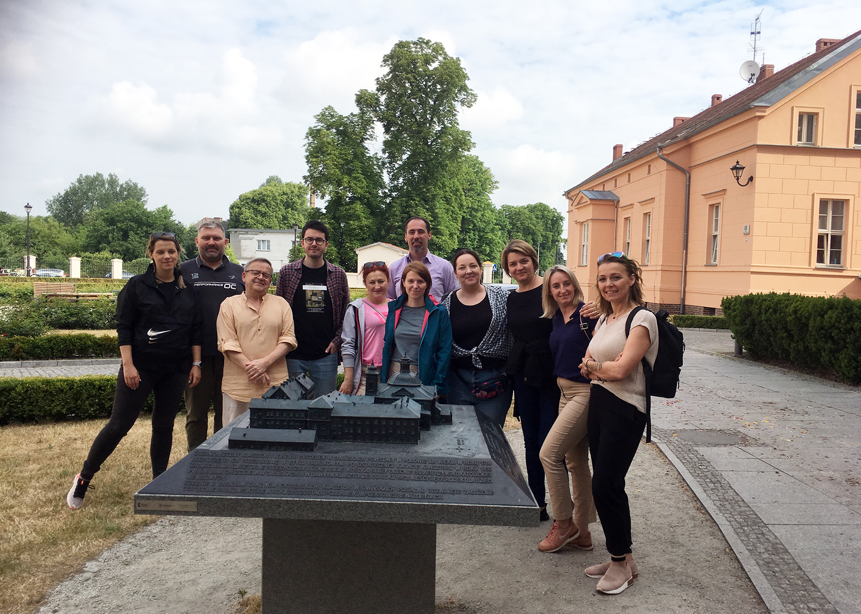 Grupa osób na zdjęciu przed makietą